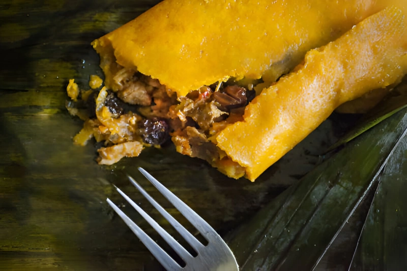 deliciosa hallaca venezolana abierta y sobre sus hojas de plátano