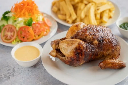 Pollo a la brasa dorado acompañado con papas fritas y ensalada
