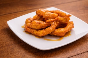 Deliciosos picarones peruanos dorados y crujientes sobre un plato blanco