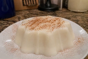 Tembleque de coco puertorriqueño servido en un plato blanco y espolvoreado con canela
