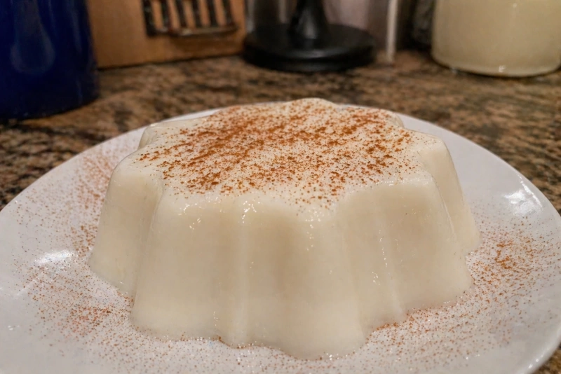Tembleque de coco puertorriqueño servido en un plato blanco y espolvoreado con canela