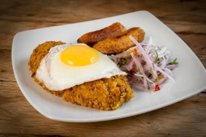 Plato de tacu tacu dorado con cebolla y ají acompañando